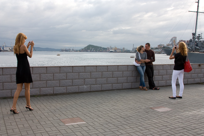 Девушки фотографируют пару на набережной