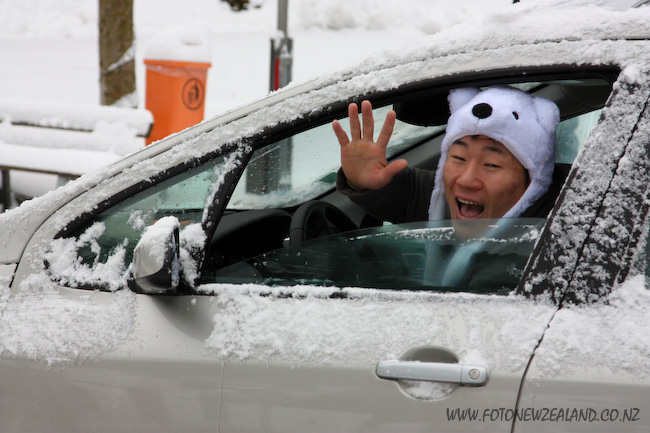Забавный водитель азиат в шапочке медведя в заснеженной Швейцарии